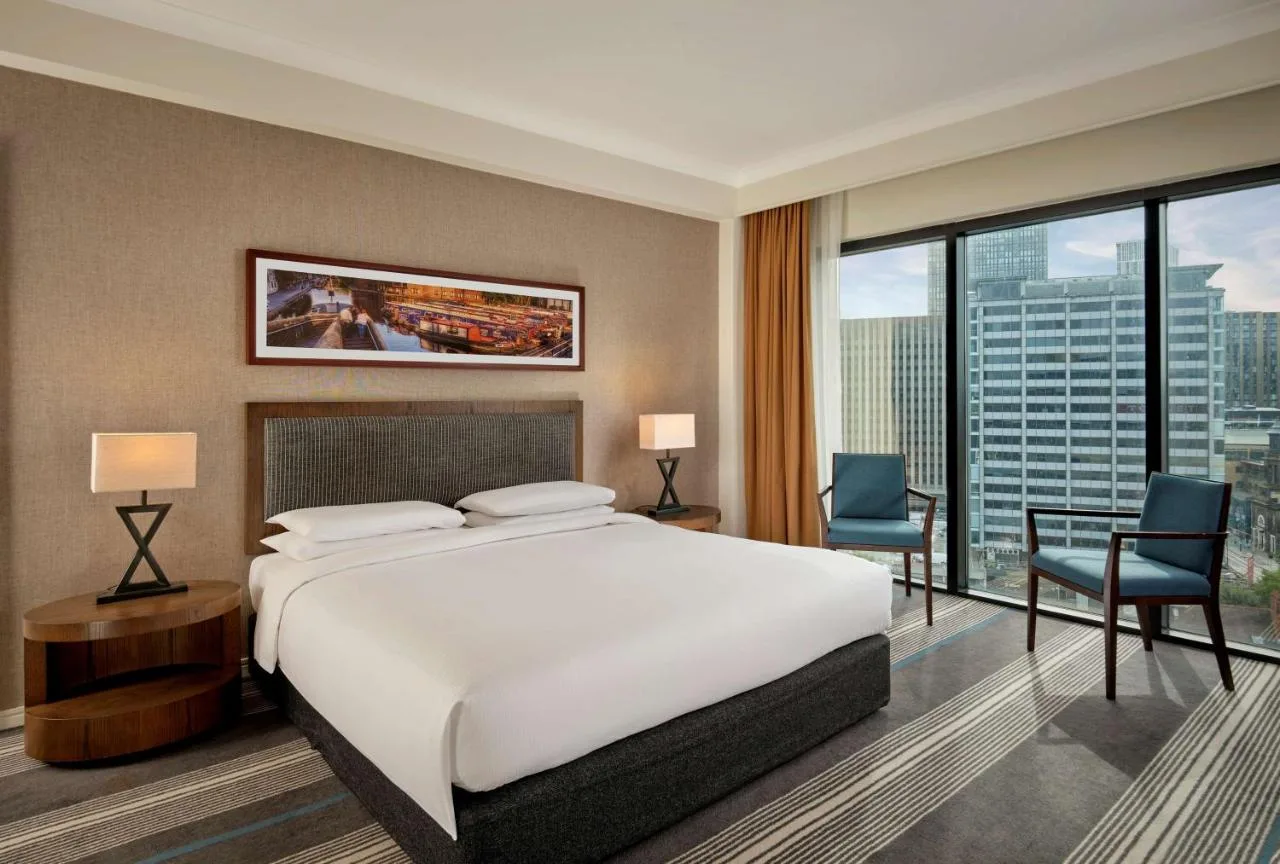 a bedroom with a large bed and a desk and chairs at Hyatt Regency Birmingham in Birmingham